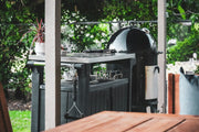 Outdoor grill on a backyard patio surrounded by greenery
